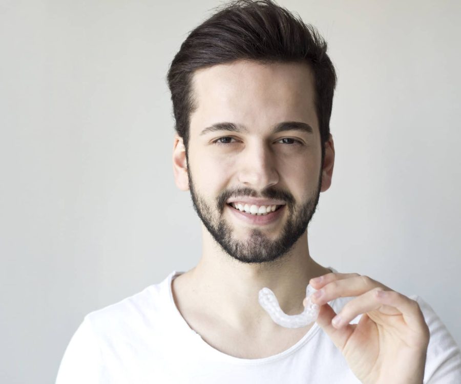 Close-up Of A Man's Hand Putting Transparent Aligner In Teeth