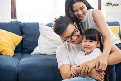 Portrait of happy Asian family spending time together on sofa in living room. family and home concept.