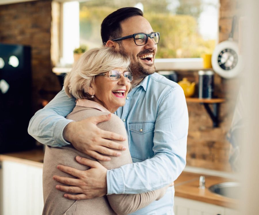Cheerful senior woman embracing her mid adult son who came to visit her at home.