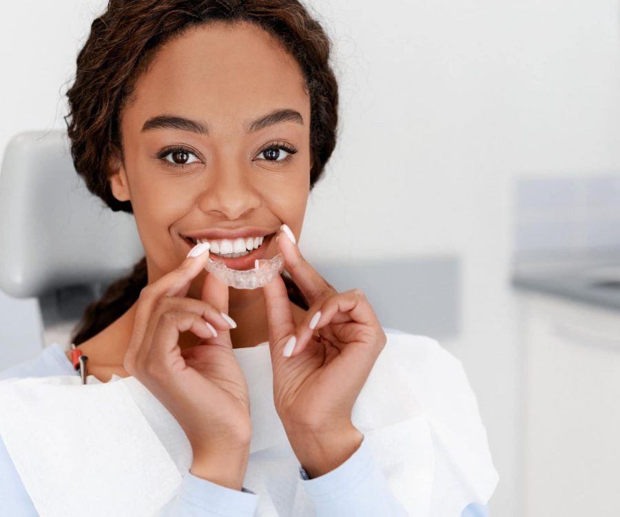 Dental Treatment Concept. Close up of young black woman holding invisible aligner, whitening tray, free space